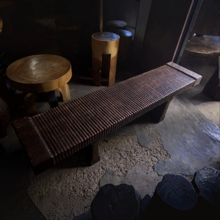 The hand-carved solid mango wood bench presented within Senja’s signature modern organic luxury branding setting surrounded by curated sculptural art furniture.