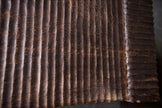 Extreme macro detail shot showing the hand-carved ridged textures and traditional fire-torched espresso finish on the solid mango wood bench.
