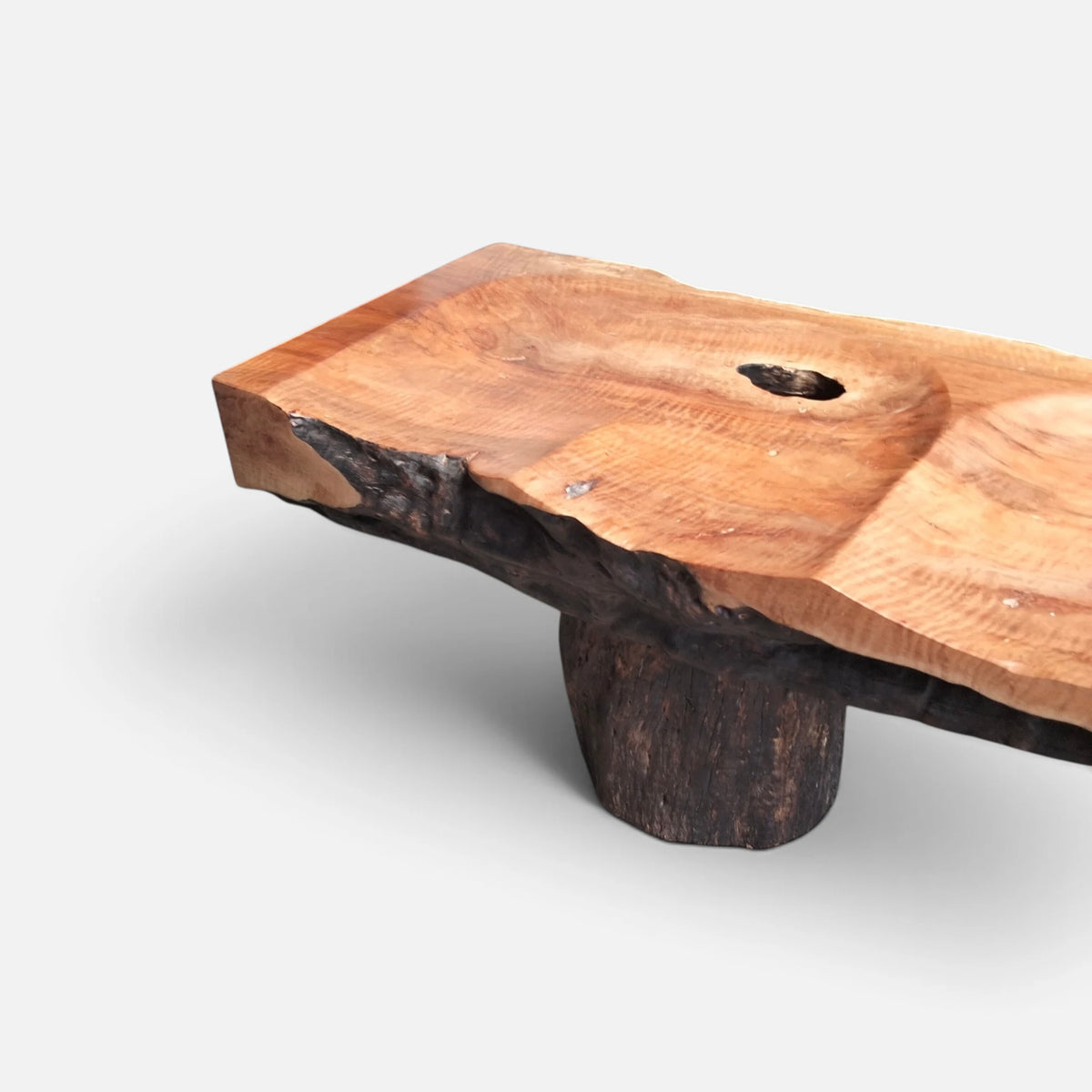 Angled perspective view of Senja modern organic bench showcasing polished live-edge lychee wood grain contrasting with a dark textured bark base.
