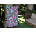 Keep Smiling (2026), an original painting by emerging Balinese artist I Made Ananda Krisna, displayed outdoors on his family’s art gallery property in Bali, beside a traditional stone structure and garden seating — curated and photographed by Senja Living.