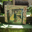 Berkaca (2026), a one-of-a-kind acrylic painting on canvas by emerging Balinese artist I Wayan Dendy Permana Putra — displayed outside his family art gallery on a grass-covered stone ledge amid tropical foliage, with a carved stone feature by the artist's father, established artist I Nyoman Bratayasa, visible behind it — photographed and curated by Senja Living.