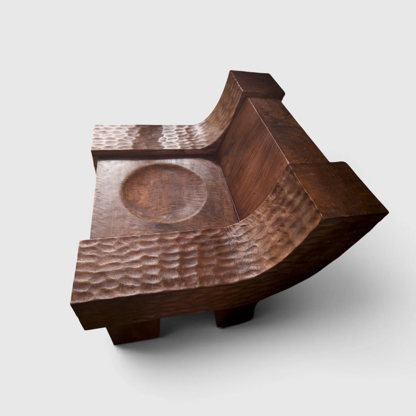 Angular view of the modern organic brutalist lounge chair No.99 by Senja Living, with a polished scooped seat center and stunning smooth backrest highlighting the natural grain of the mango wood.