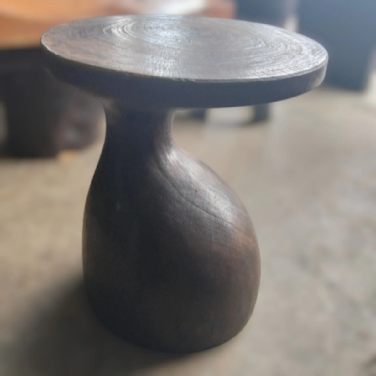 Showroom view of the Sculptural Gooseneck Espresso Side Table styled inside a modern luxury lounge interior setting from Senja Living.