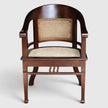 Front detail view of the Colonial Art Deco Teak Tub Back Armchair by Senja Living, highlighting the hand-woven cane seat and curved elegant teak frame.