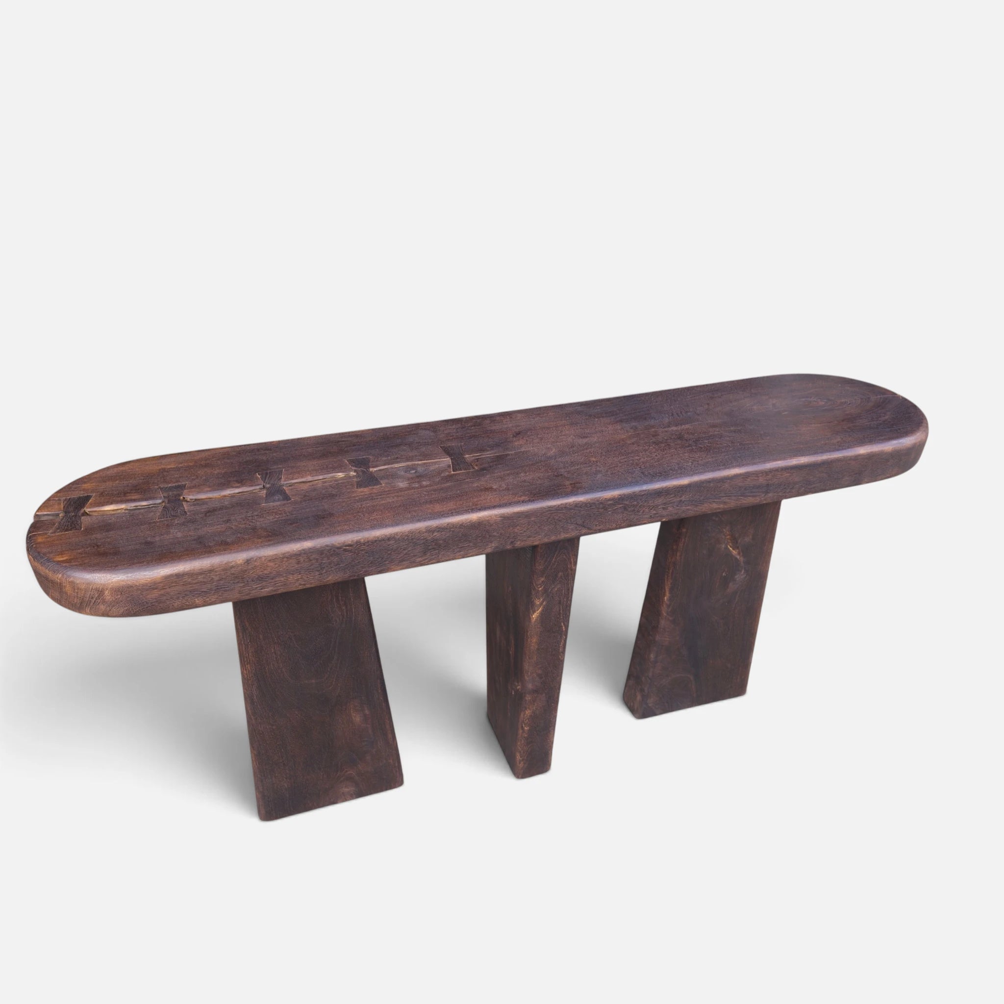 Elevated three-quarter studio shot of the solid mango wood console table showcasing the three monumental angled block legs and hand-keyed butterfly joint details.