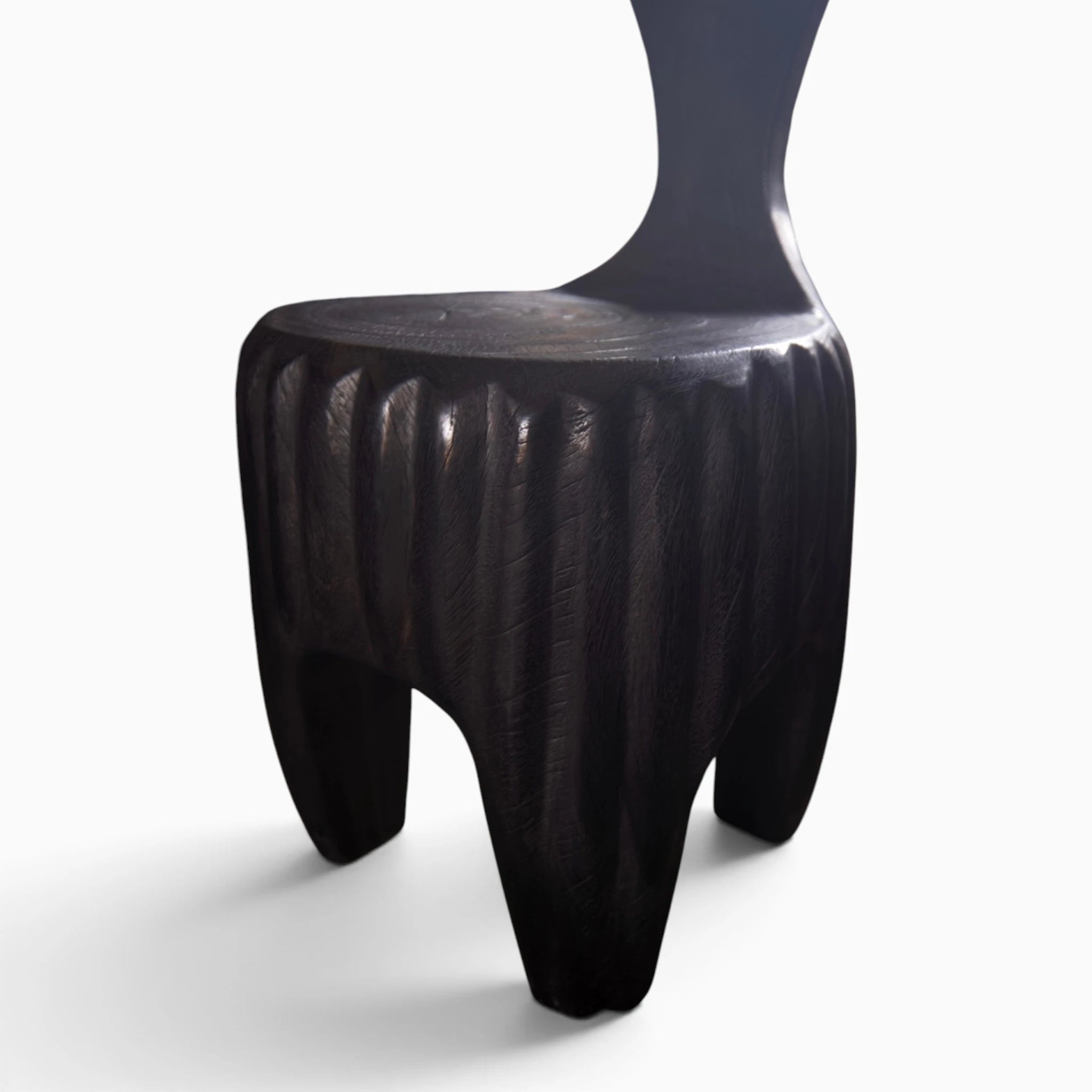 The Senja Living Bespoke Spoon-Back Chair is hand-sculpted from solid mango wood showcasing deep carved vertical fluting along the textured cylinder base.
