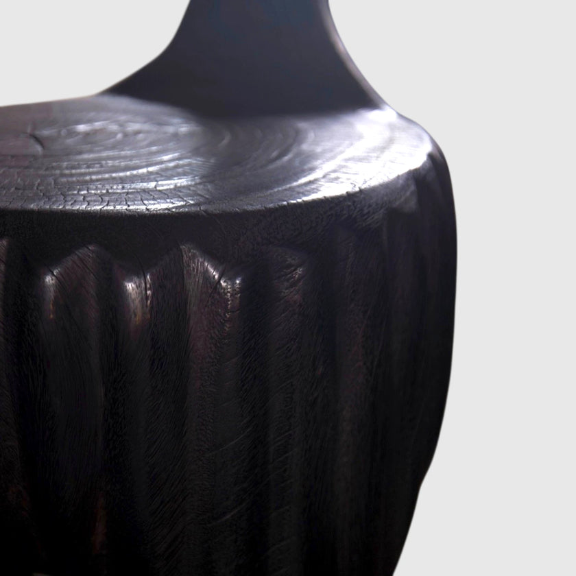 The Senja Living Bespoke Spoon-Back Chair is hand-sculpted from solid mango wood showcasing a polished seat surface with dense natural wood grain rings.