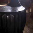 Close-up lifestyle view of the Senja Living Bespoke Spoon-Back Chair highlighting the deep fire-charred fluted base under natural sunlight.