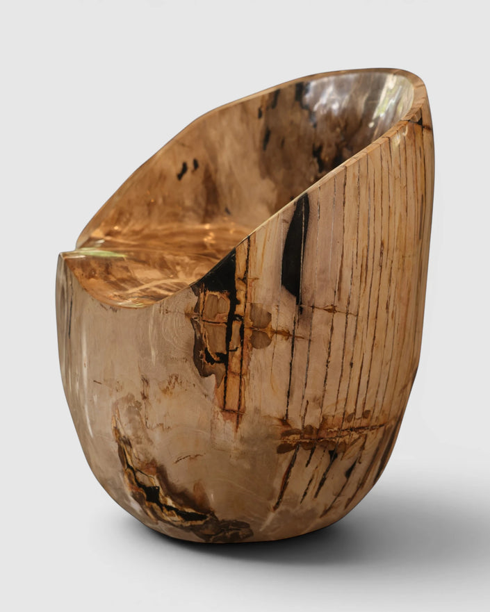 Hero view of the Senja petrified wood warm beige statement dining chair and accent chair showing the contrast between its warm refined organic bark exterior with remarkable dark brown and black vertical fossil streaks and highly polished scooped seat.
